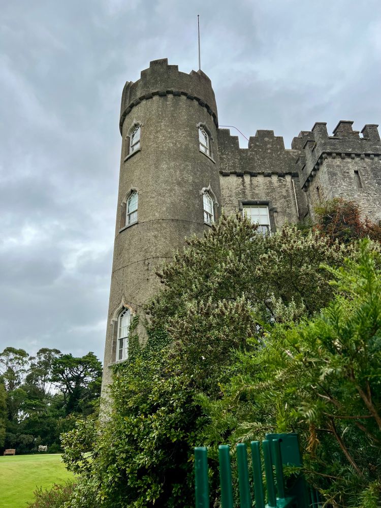 4 stöckiger Steinturm, Teil eines historischen Gebäudes; grüne Büsche
