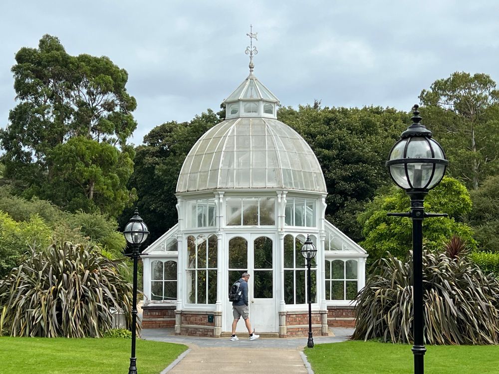 Grass left and right; path leading up to a elaborate greenhouse; trees in the background