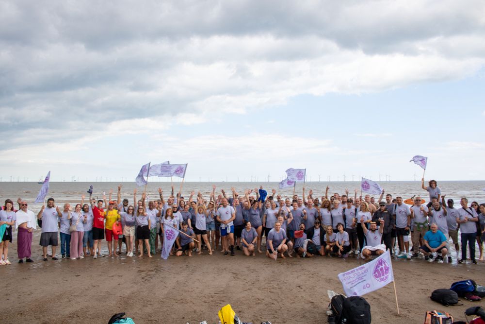 A group of people stood on the beach holding Big Splash flags