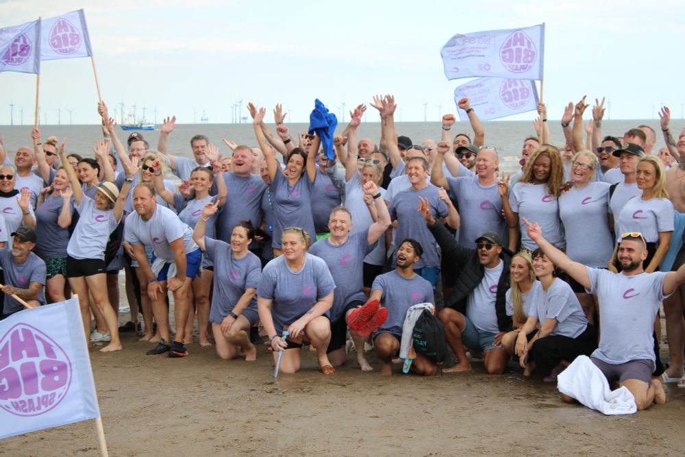 A group of people stood on the beach holding Big Splash flags