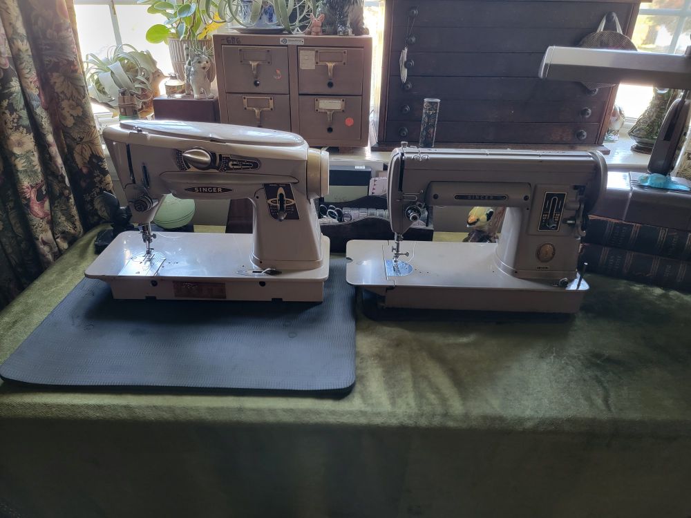 Two vintage, all-metal sewing machines atop my work desk in my study.