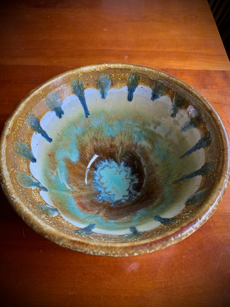 A ceramic bowl with blending colors of different shades of blues and browns and off white 