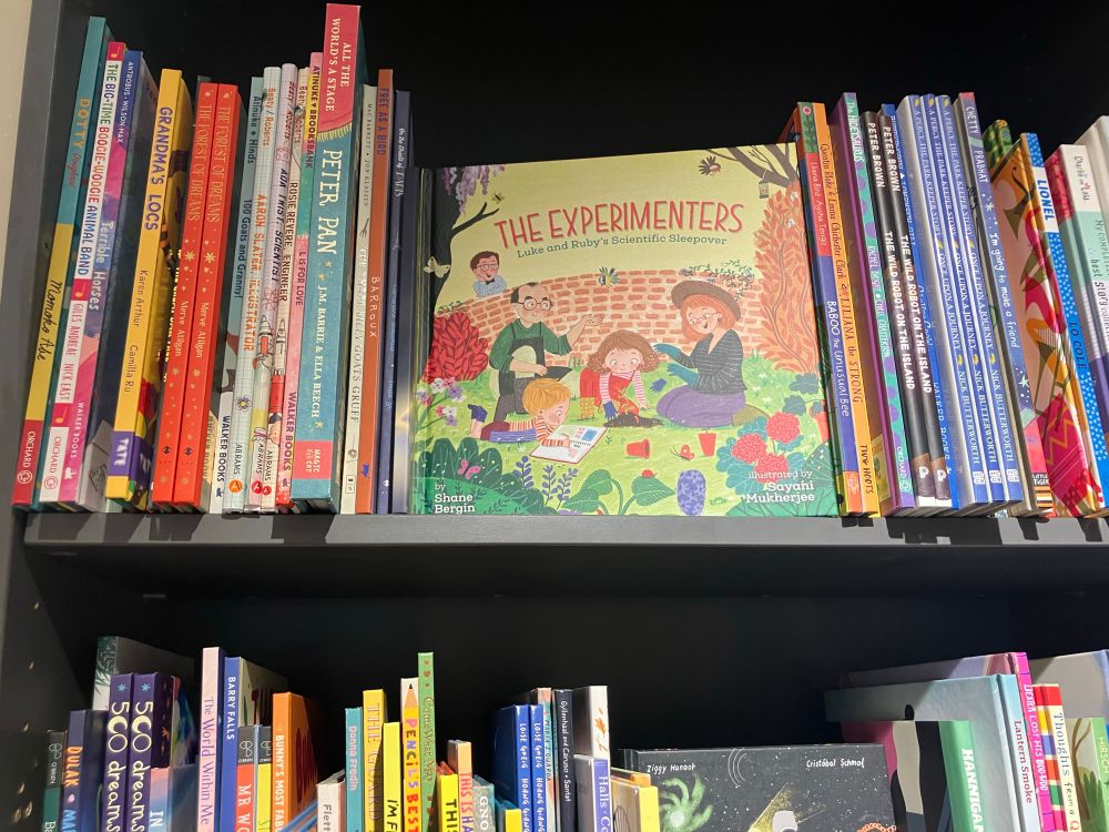 The Experimenters book on bookshelf facing out with other books near it 