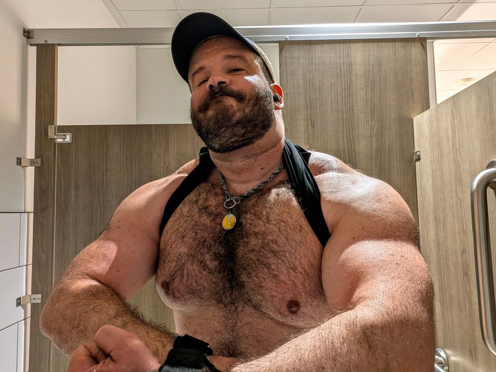 Guy in black tank top flexing his chest, arms, and shoulders.