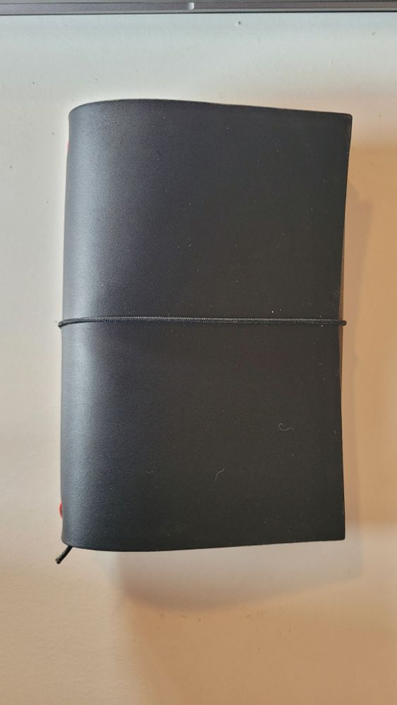 Ein schwarzes Notizbuch aus Leder von oben.