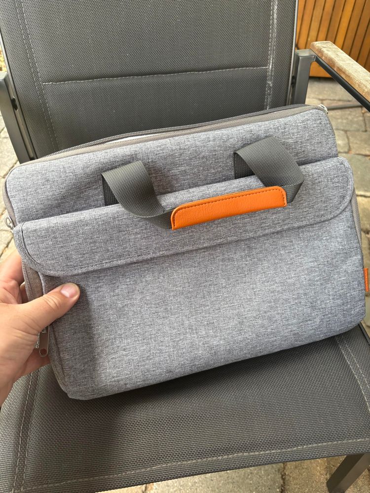 Eine graue Laptoptasche für maximal 15“-Geräte würde ich sagen. Der Griff ist aus einem dunkelgrauen Sicherheitsgurt-Stoff mit einem Absatz aus hellbraunem Kunstleder