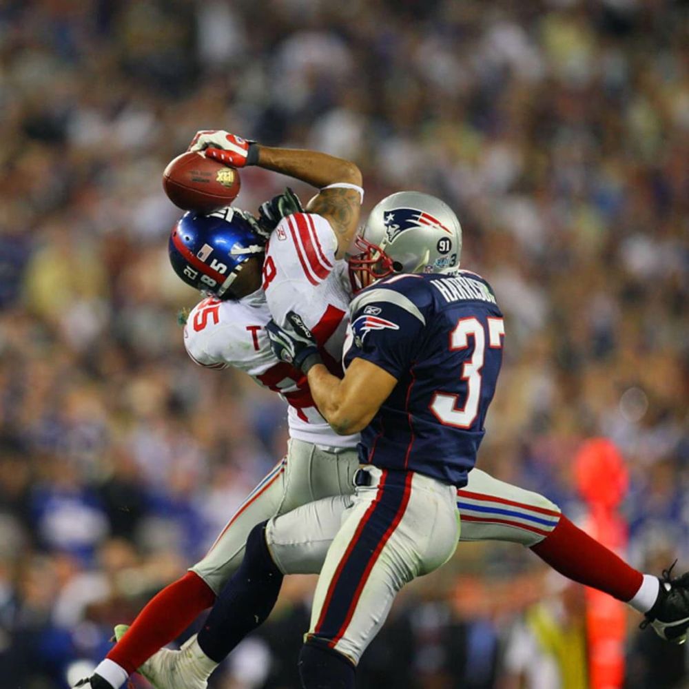 David Tyree of the New York Giants uses his helmet to help catch a football, setting up the Giants Super Bowl win over the undefeated New England Patriots