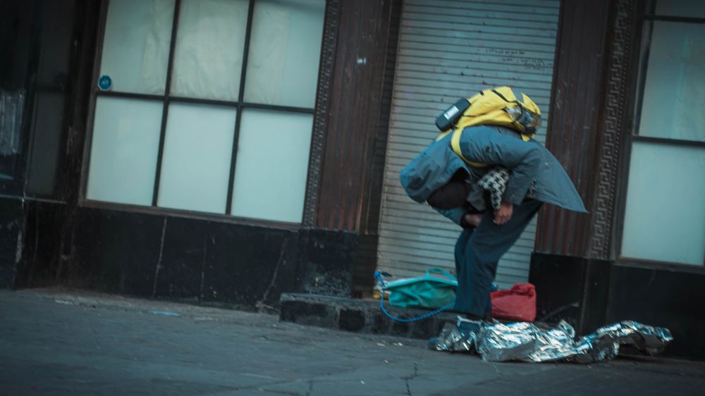 A street person up to something with belongings nearby