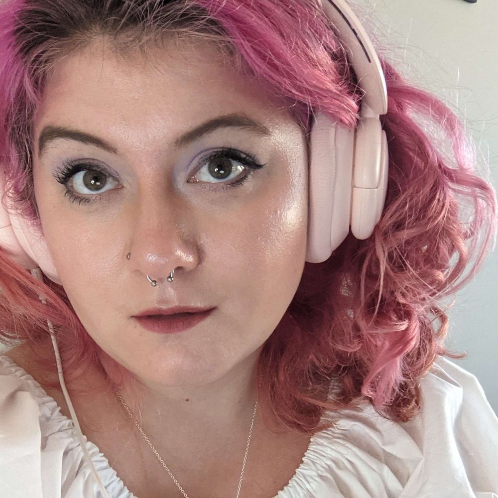 amber's twitter profile picture in 2021/2022 @thespacejamber. she is a white woman with pink curly hair, large breasts, and a white shirt.