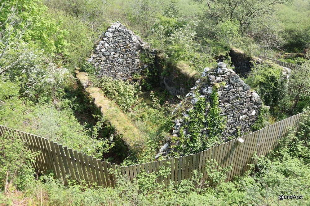 Cottage, von dem nur noch die Außenmauern stehen, und auch die sind schon be- und teilweise überwachsen. Ein Holzzaun ringsherum sichert die Ruine vor unbefugtem Betritt.