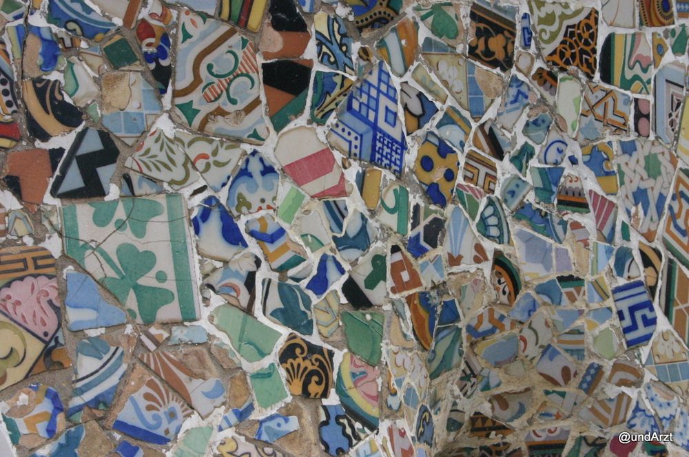 Detail einer Wand, auf der bunte Scherben alter dekorativer Fliesen scheinbar wahllos zu einer neuen Oberfläche verklebt sind