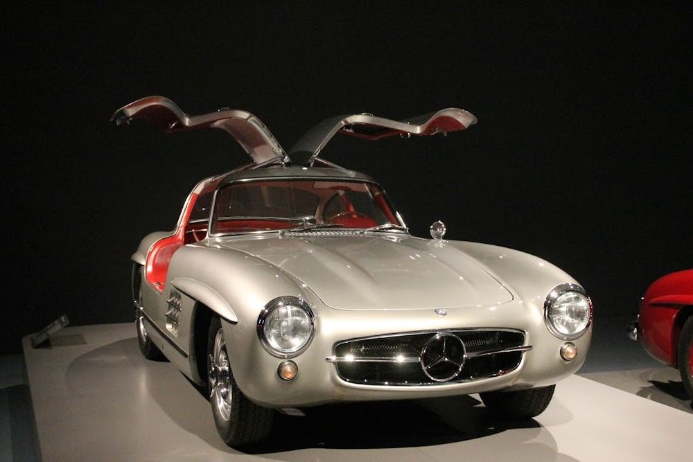 Mercedes Oldtimer mit Flügeltüren (offen), auf einem Sockel zum Bewundern ausgestellt.