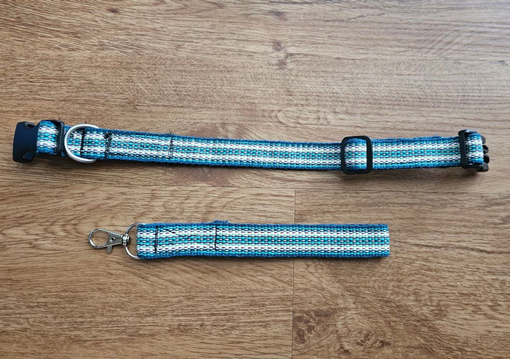 A handwoven dog collar and matching wrist loop keychain. They have a striped pattern in dark blue, light green, gold, teal, and burgundy.