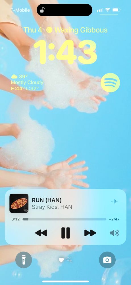 my lockscreen. the background is nct wish's hands in the sky with bubbles from their poppop promotions. the song playing is run by han and the time is 1:43