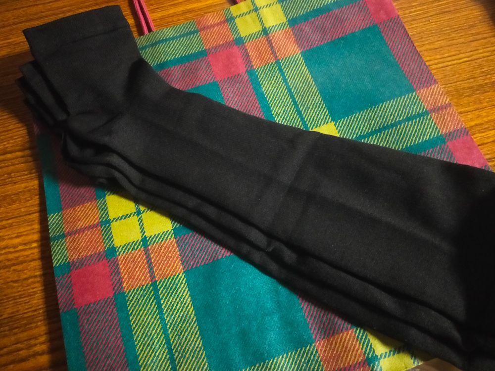 黒色の着圧ソックスの写真。タカシマヤのチェックの紙袋の上に置かれている