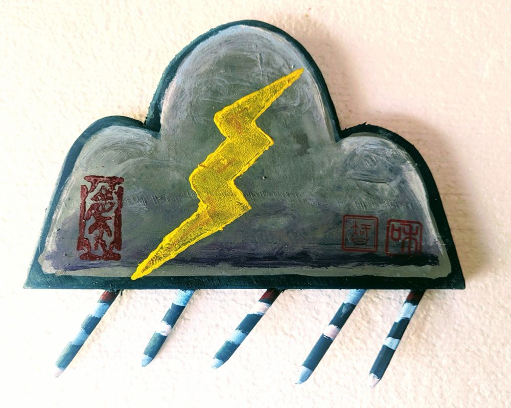 An ema prayer plaque made of painted wood. It’s about 8 inches wide and shaped like a stylized cloud then painted a stormy gray. A yellow lightning bolt is in the center and two glyphs on the bottom invoke spirit ancestors, harmony, and wisdom. Beneath the cloud are five short sticks at a slant that are painted like rain (striped). 

Southern Arizona has had little appreciable rain since September. Our winter rains are crucial for desert plants and animals and help protect wooded areas from wildfire. The wildfire season starts in May. 