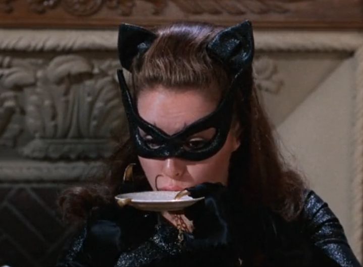 Catwoman drinks milk from a saucer