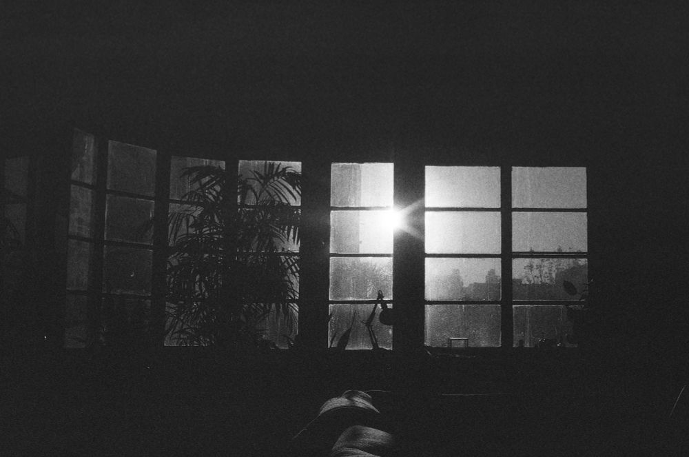 A bright sunrise pierces the dark living room of a Los Angeles apartment. 
