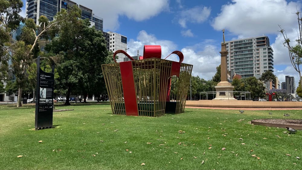 A public Christmas decoration sits in Light Square, Adelaide. Constructed of a metal cage with a bow on top. More of a prison to sit in than a chocolate box. 