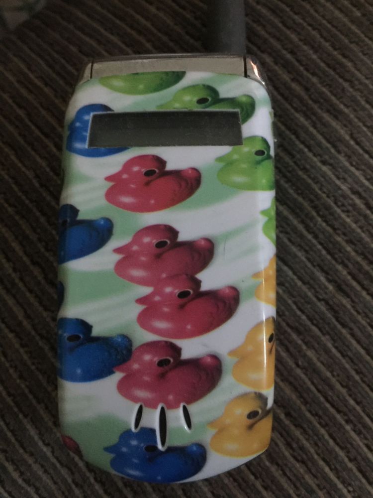 An at&t flipphone from too long ago with a rubber ducky phone case snapped on it. I'm talking this flipphone was before colored screens were a standard thing, the before times.