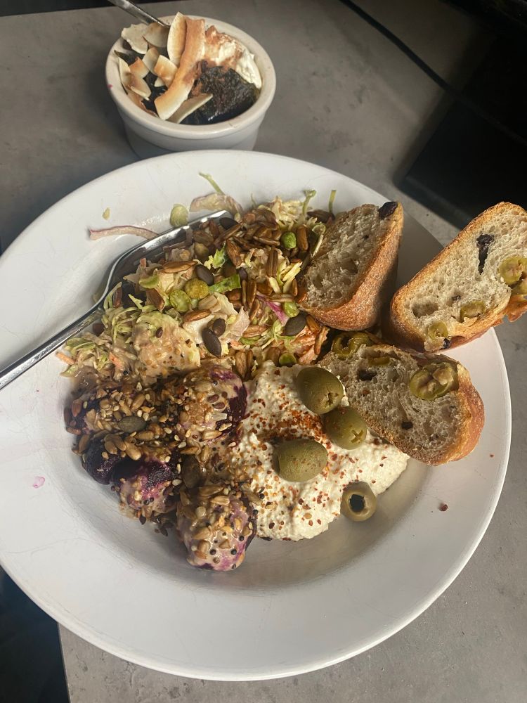 Plate full of salad and hummus and a pudding topped with different fruit and nuts