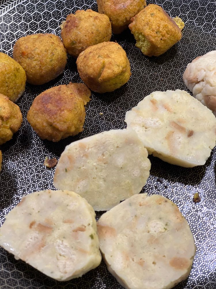 Eine Bratpfanne mit Falafel-Bällchen und aufgeschnittenen Semmelknödeln