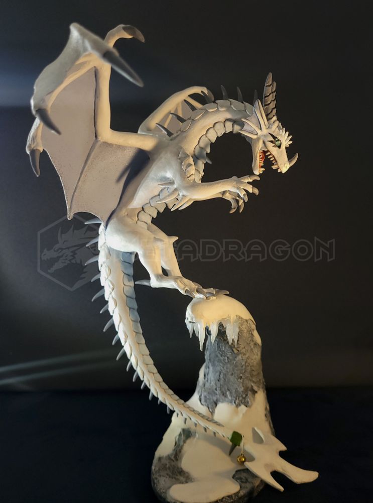 A modeled figurine of a white dragon sitting on a mountain ledge.