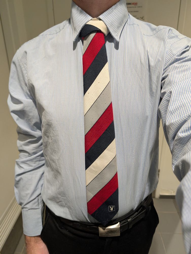 Torso wearing a diagonally striped red, navy white and grey tie. Playboy logo in the bottom corner.