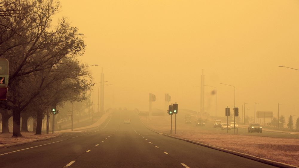 Street scene with very limited visibility due to heavy smoke development. The sky has a yellowish-orange tint, indicating increased air pollution.