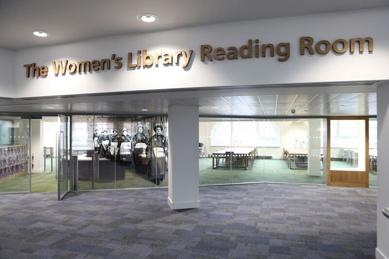 The Women's Library at LSE. A view of the Reading Room from outside with its lines of desk and suffragette print on the glass.