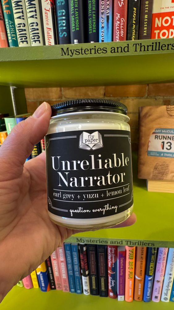 A candle in a bookstore labeled "unreliable narrator"
