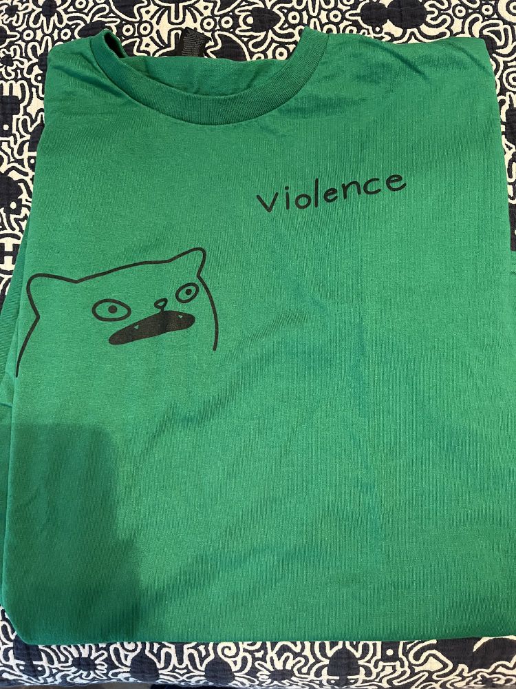 Kelly green t-shirt with a poorly drawn cat face implying violence