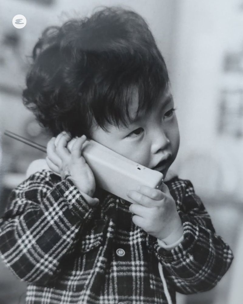 Black and white photo of liddul hongjoong holding a phone to his ears