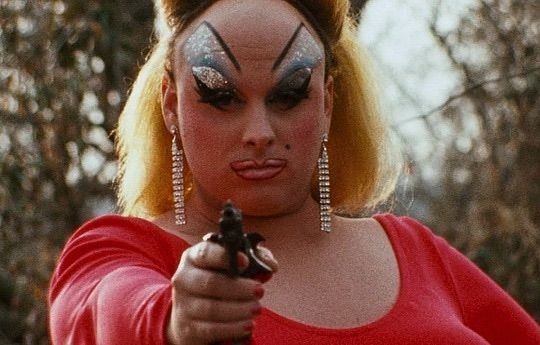 Divine holding a gun