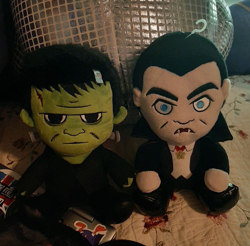 2 universal monsters plushes, one of Frankenstein's monster (left) and one of Dracula (right) 
