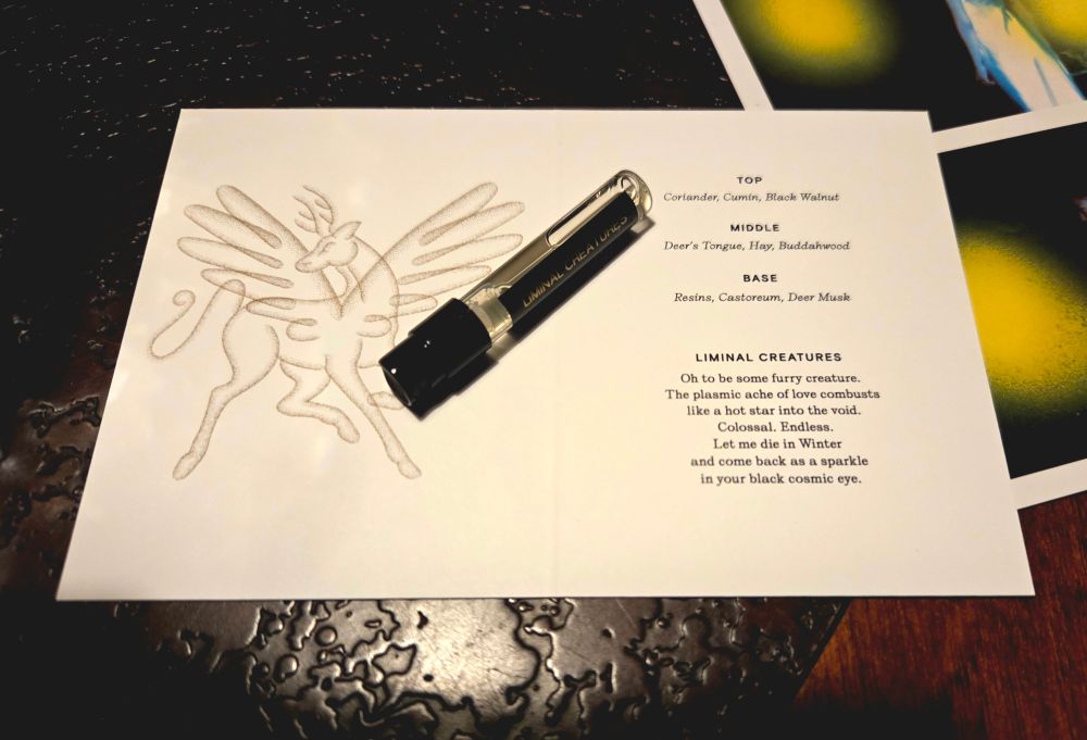The scent card for Liminal Creatures with the sample sprayer lying on it. Top notes are Coriander, Cumin, and Black Walnut. Middle notes are Deer's Tongue, Hay, and Buddahwood. Base notes are Resins, Castoreum, and Deer Musk.

A poem at the bottom accompanies the scent. It reads: "Oh to be some furry creature. The plasmic ache of love combusts like a hot star into the void. Colossal. Endless. Let me die in Winter and come back as a sparkle in your black cosmic eye."