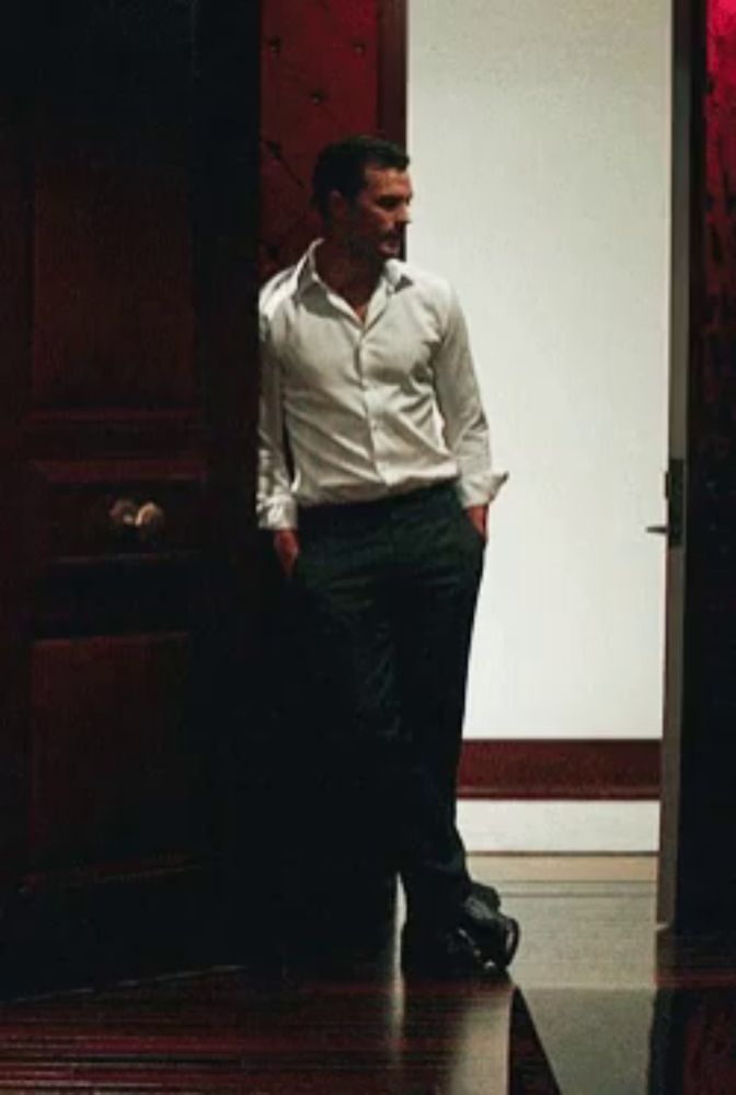 a man in a white shirt is leaning against a door