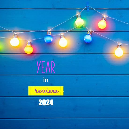 Reads 'Year in Review 2024' against a blue wall with colourful fairy light bulbs.