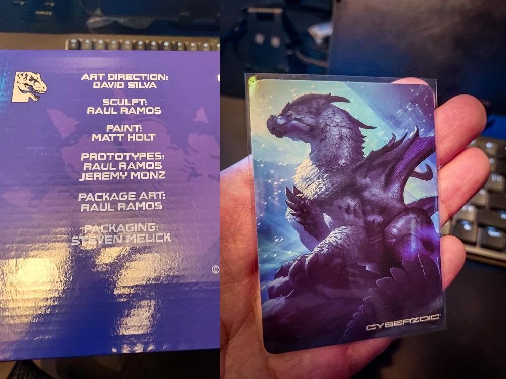 a side view of the box art showing the names of all of the artists that worked on the figure and their roles. On the second half of the image the trading card version of the dragon illustration on the box is shown being held by the artists hand.