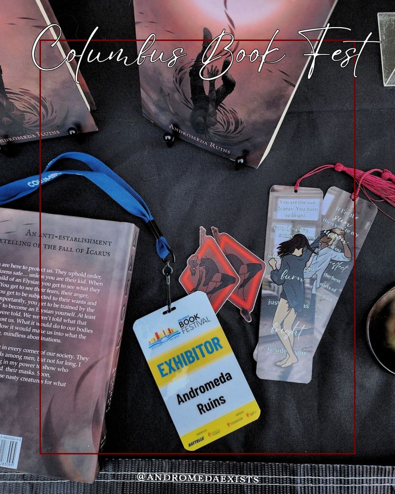 a top down photo of my table set up at Columbus Book Fest showing a couple copies of ΔΆΙΟΣ, some Icarus stickers, booksmarks, and my exhibitor badge. There is white text at the top that reads Columbus Book Fest.