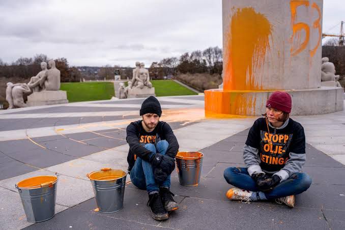 Bilde som viser aktivistene med maling foran monolitten. På t-skjortene deres står det «STOPP OLJELETING»