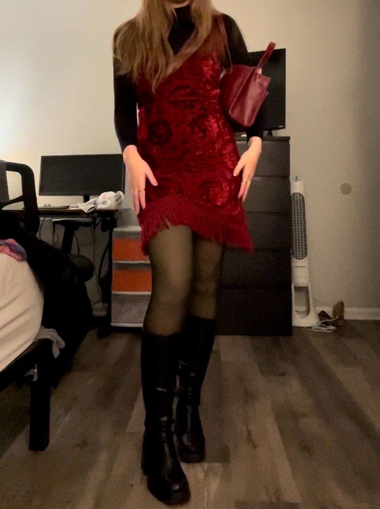 Black turtleneck with a velvet red mini dress. The red dress has a plunging v neck with swirl patterns and a fringe on the skirt. Wearing sheer tights and black knee high heeled boots. Red faux snakeskin purse.