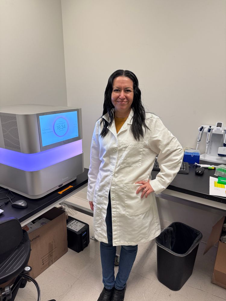 Latina scientist in front of a sequencing machine 