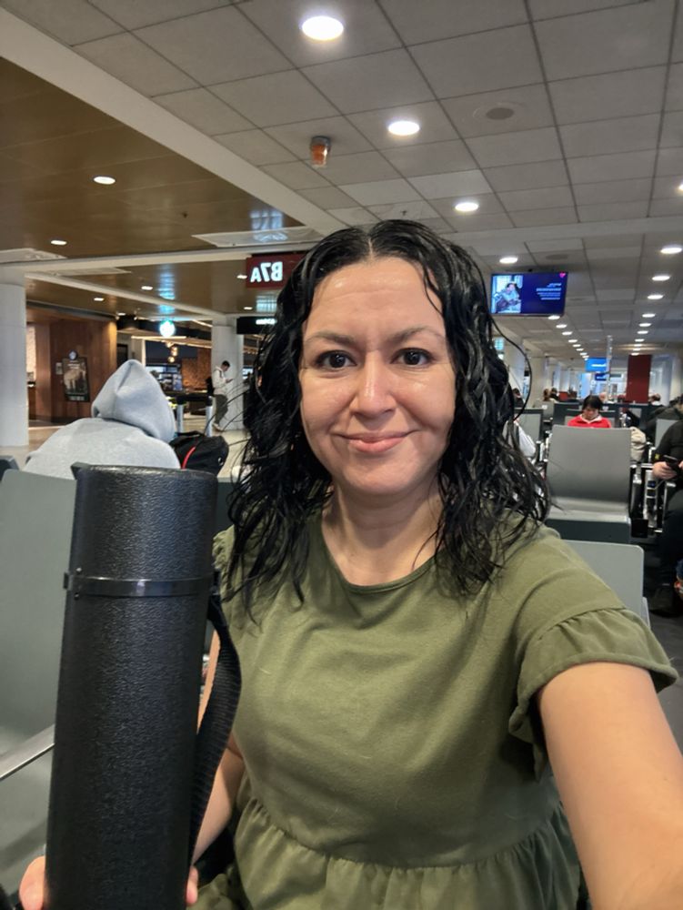 Dr Tracie Delgado, Professor of Biology at Seattle Pacific University holding a research poster tube at the airport 