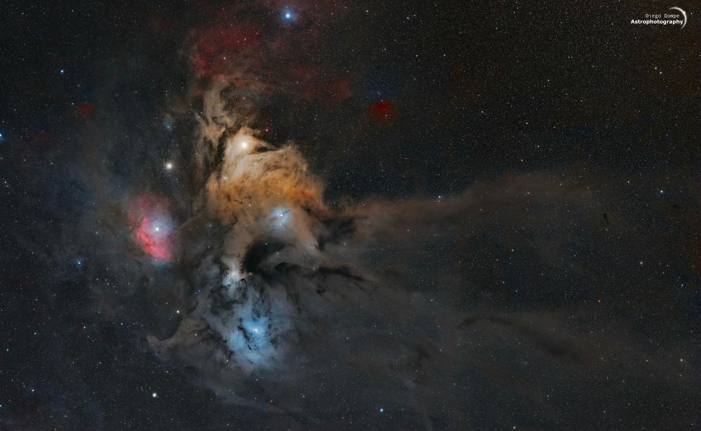 Photo of the Rho Ophiuchi area of the sky, showing blue, red and yellow tones between dark nebulae