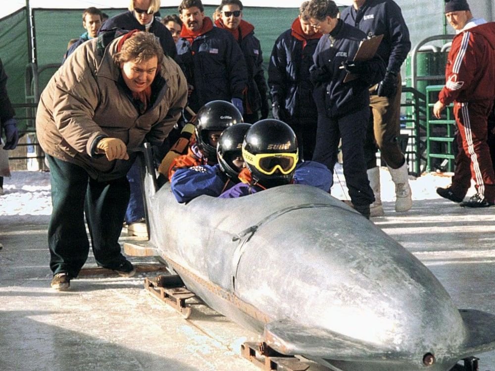 Scene from the early 90s movie cool runnings. 
A bunch of scared Jamaicans in a metal prototype unpainted bobsled.. being pushed by a fat (Canadian? I really can't remember if he was American or Canadian)