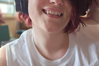 A selfie of myself, cropped to the lower half of the face. I'm showing off my teeth, highlighting that I have extended canines.