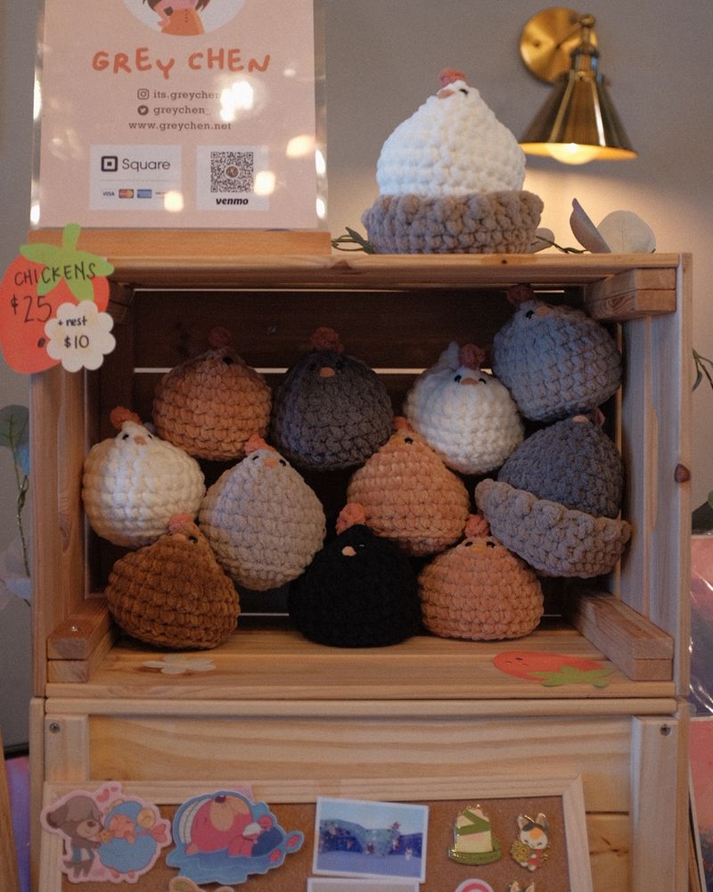 A photo of a crate full of crochet chickens. The chickens are various colors including, white, brown, grey, and black