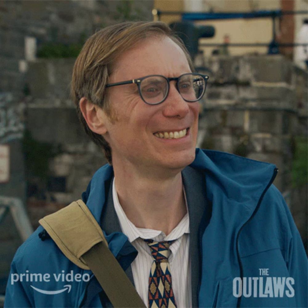 a man wearing glasses and a blue jacket with the outlaws written on it