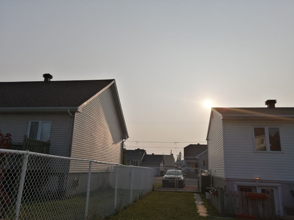 Photo of the backyard with the sun setting in the horizon.